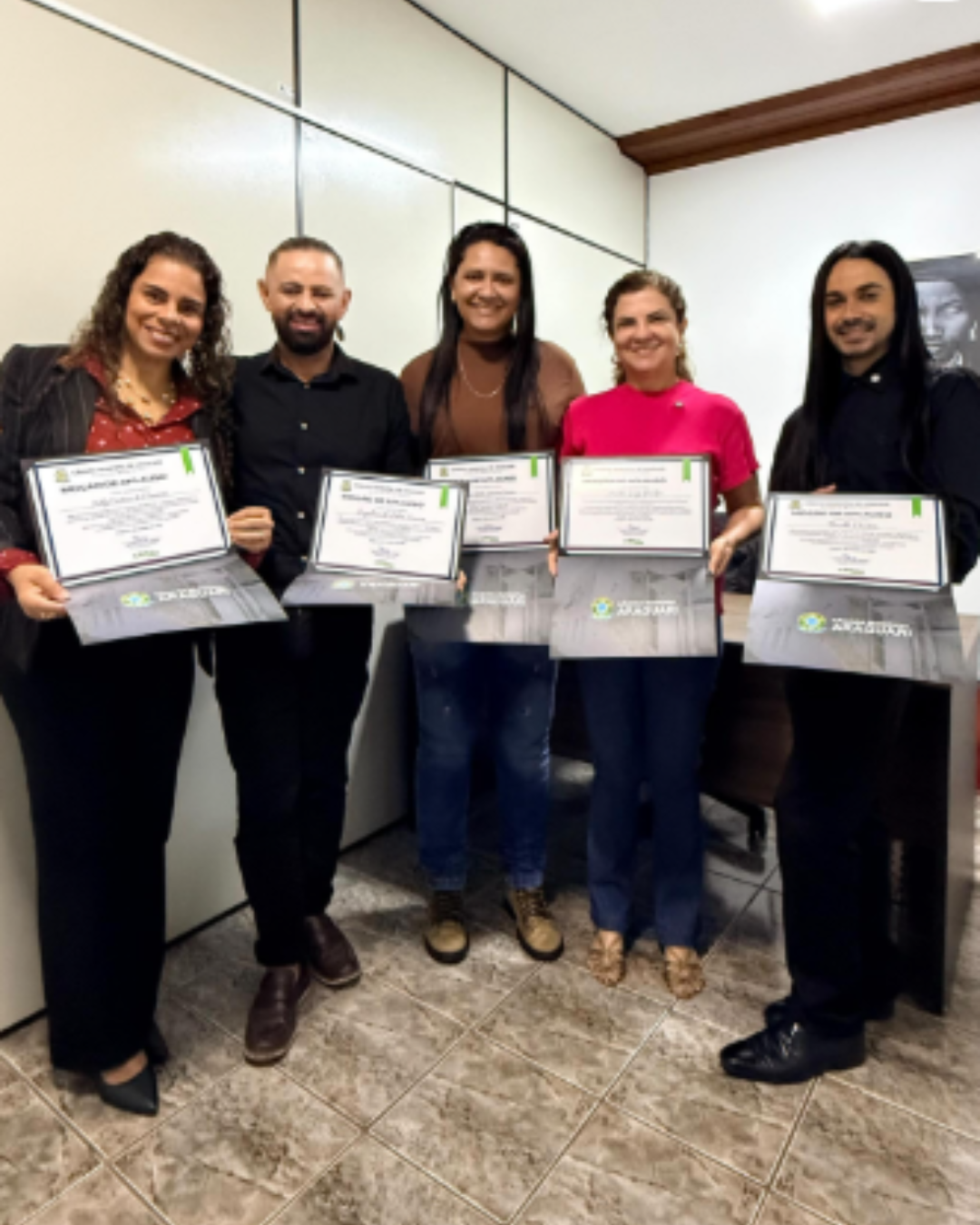 Grupo de participantes reunido no palco diante de uma projeção com a frase “Nenhum Direito a Menos”.